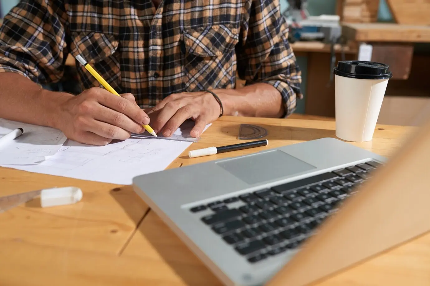 Mittlere Körperpartie eines anonymen Mannes beim Skizzieren am Arbeitsplatz.